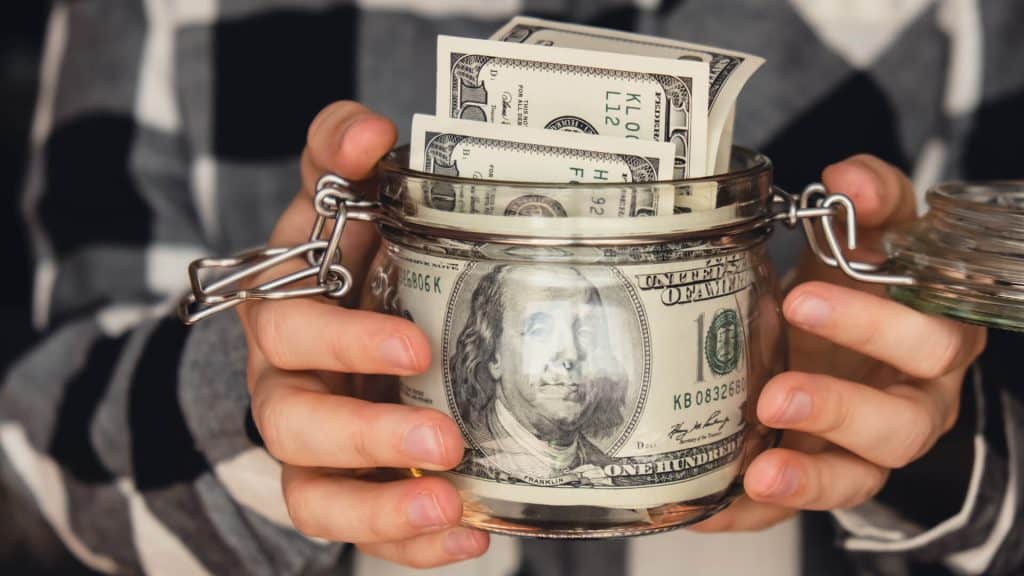 Hands holding a jar of money, representing the savings for 'Scrum certification cost'.